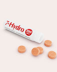 A white tube labeled 7-Hydro 200 MG lies open with five round, orange chewable tablets scattered in front of it on a light background.
