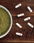 Kratom capsules spread out next to kratom powder