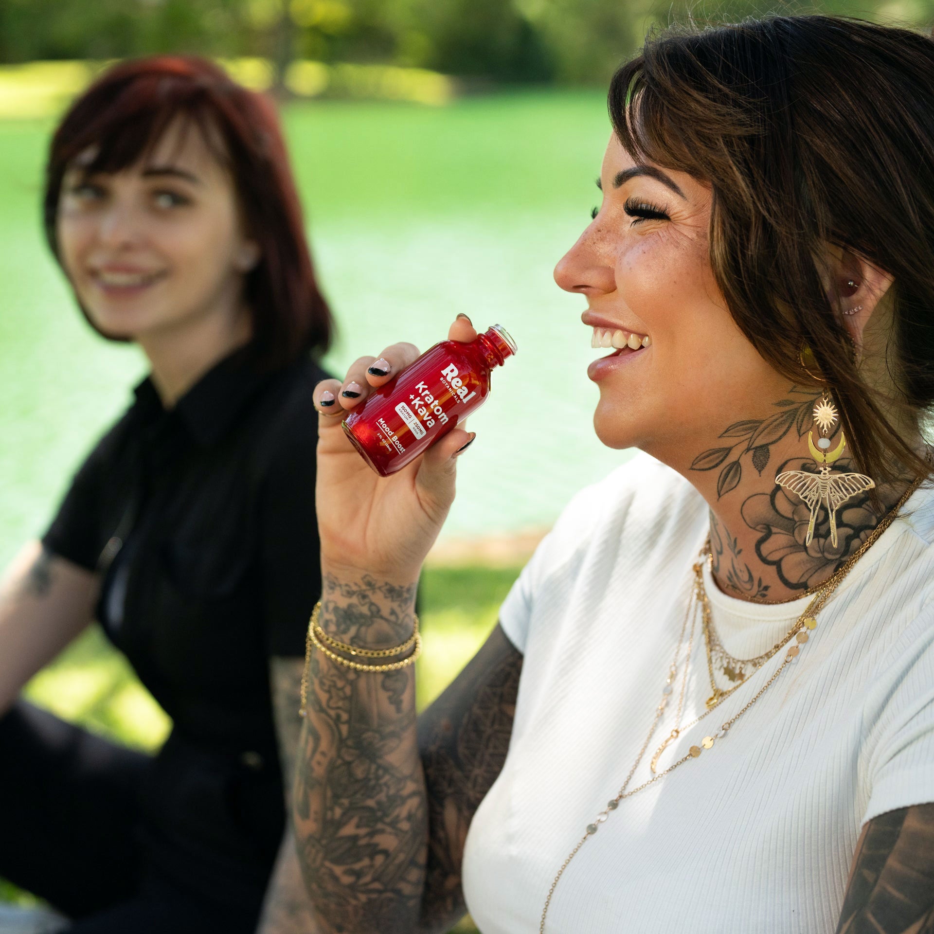 Two smiling women sitting together and drinking Kava, enjoying a relaxed moment
