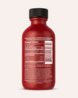 A red bottle of Real Botanicals Kratom Shot with a white label showing product facts, ingredients, and manufacturer information; the cap is sealed and the background is off-white.