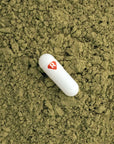 Kratom capsule on top of kratom powder